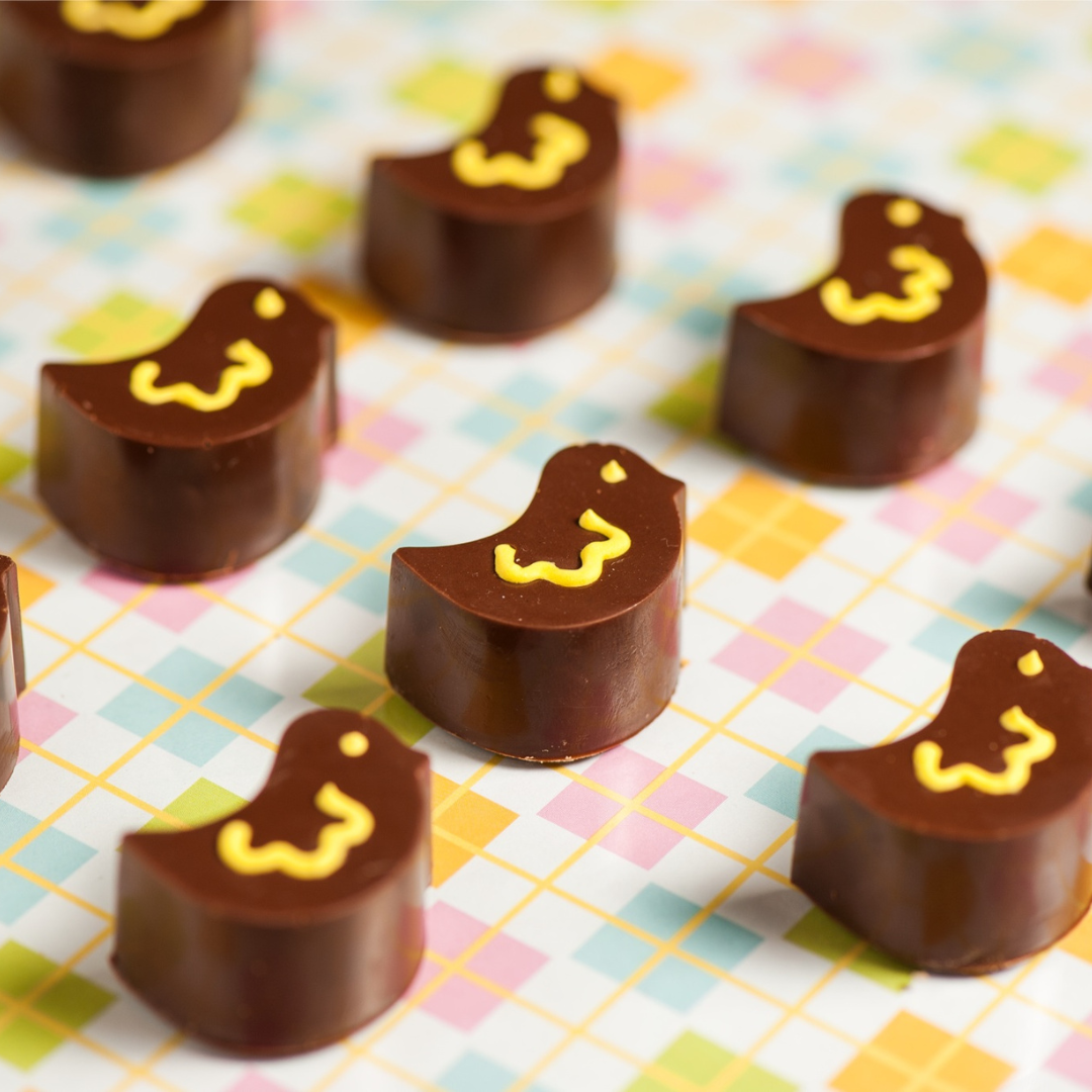 chocolate bonbons moulded into bird shapes with yellow piped
detail, arranged on a yellow and pastel checked tablecloth