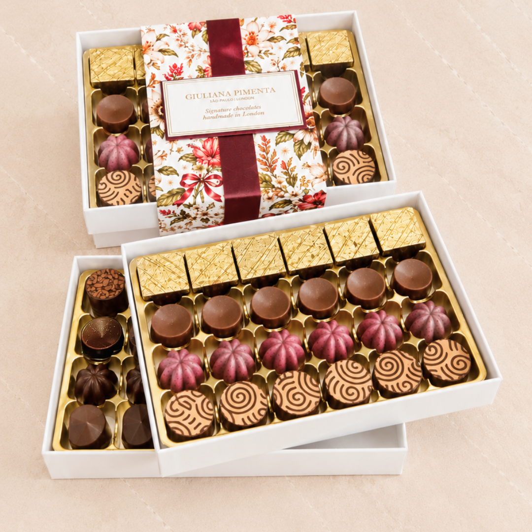Forty-eight chocolates in an open box with a burgundy ribbon, eight flavours from both Christmas collections