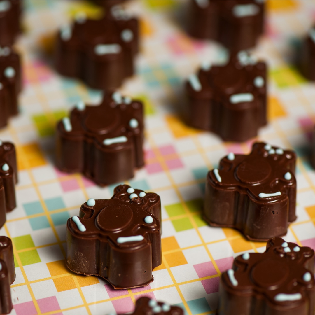 Teddy bear shaped chocolates for a birthday party with light blue details piped in royal icing