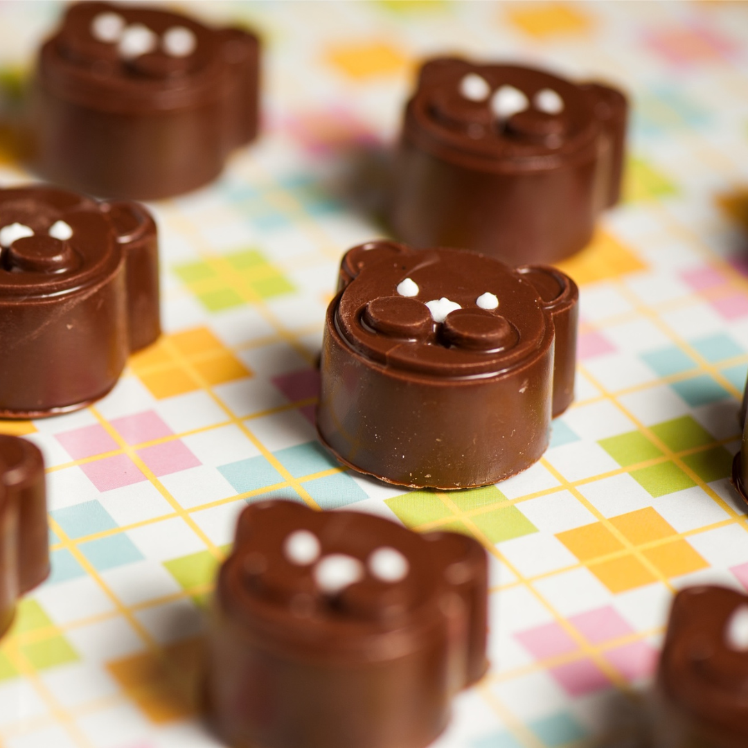 chocolate bonbons moulded into teddy bear shapes with white dot
faces, on a pastel checked tablecloth
